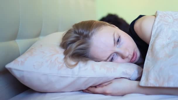 Молодая женщина разговаривает с парнем, лежащим в постели рано утром — стоковое видео