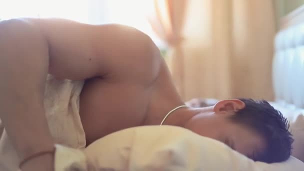 La mujer se despierta y habla con el novio musculoso dormido en la cama, temprano en la mañana — Vídeos de Stock