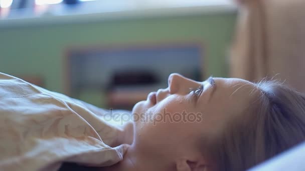 Atraktivní líná blond dívka leží v posteli v časných ranních hodinách — Stock video