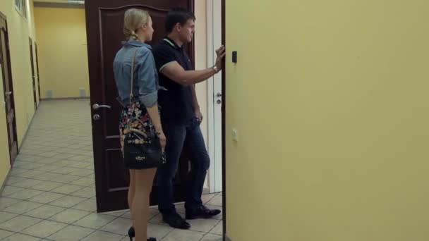 Jovem menina atraente caminha ao homem disputa na porta no corredor do escritório — Vídeo de Stock