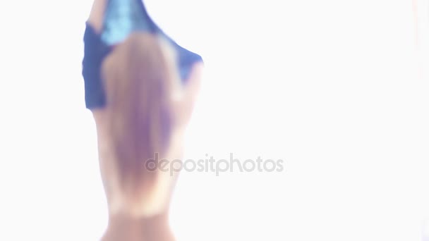 Silhouette einer jungen sexy Frau, die sich vor hellem Fenster umzieht — Stockvideo