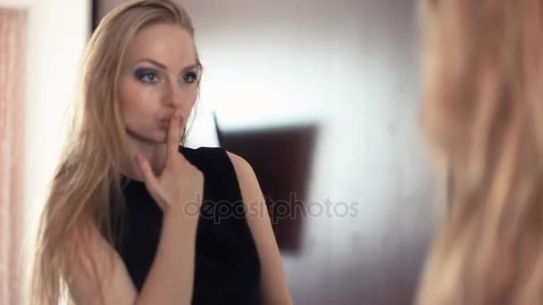 Ung vacker blond lekfull tjej tittar in i spegeln, skicka air kyssar — Stockvideo