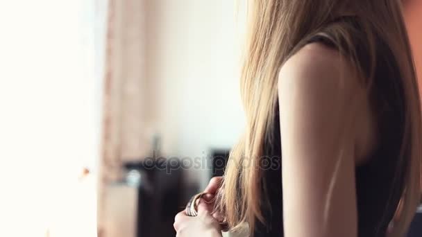 Jovem mulher loira coloca pulseiras pilha no braço na sala de estar — Vídeo de Stock