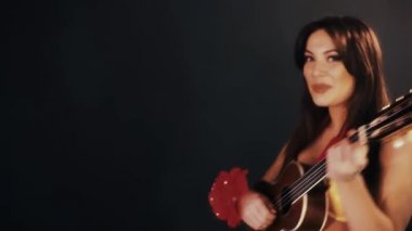 Siyah odasında ukulele gitar çalmak hawaiian elbiseli çekici esmer kadın