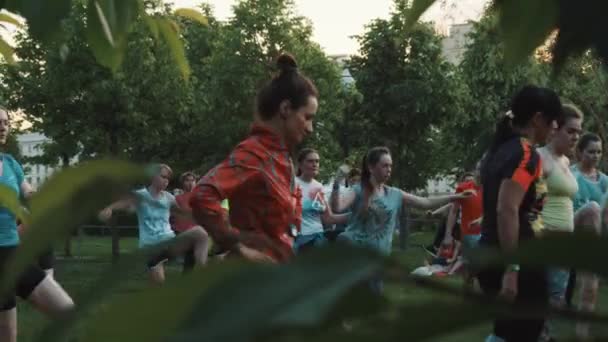 MOSCOW, RÚSSIA - JUNHO 20, 2016: Grupo de fitness feminino que alonga as pernas no gramado verde do parque da cidade — Vídeo de Stock