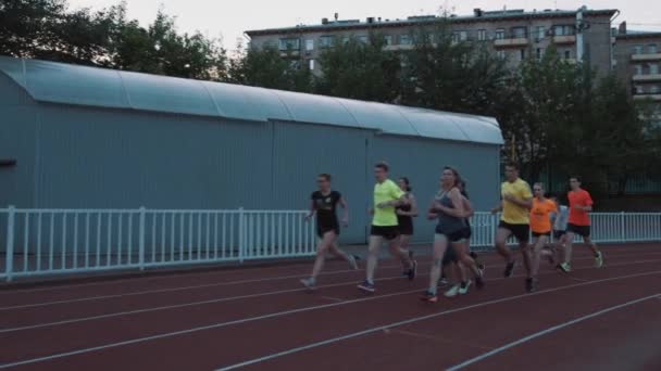 MOSCOW, RÚSSIA - JUNHO 20, 2016: Grupo de pessoas correndo em pista de estádio ao longo de construção de metal — Vídeo de Stock