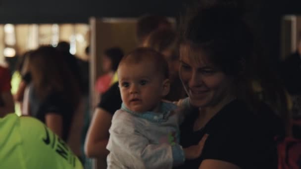 Moskau, russland - 20. juni 2016: frau mit kind auf händen spricht mit freiwilligen helfern bei überfüllter veranstaltung — Stockvideo