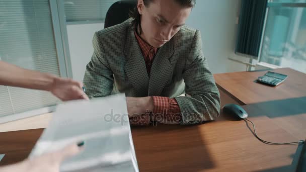 Hands put big pile of paperwork on table of tired office worker in plaid jacket — Stock Video