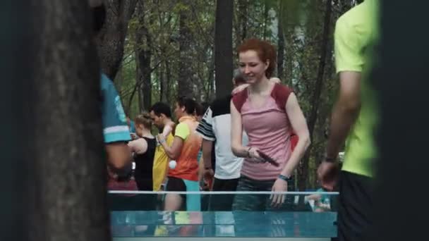 MOSCOW, RÚSSIA - JUNHO 20, 2016: Menina de cabelos vermelhos jogando ping pong com dois homens no parque da cidade, lau — Vídeo de Stock