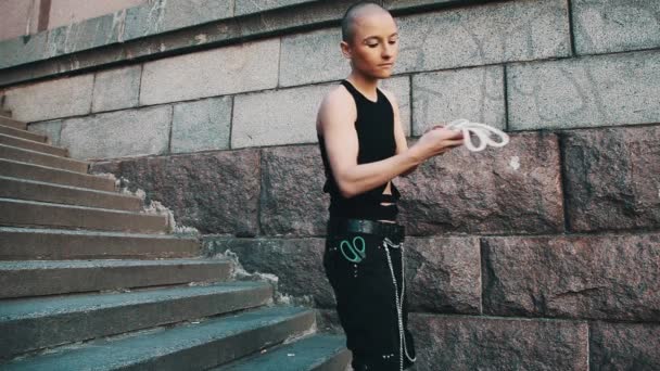 Androgyne queer meisje in gescheurde zwarte shirt, tonen truc met touw en schaar — Stockvideo