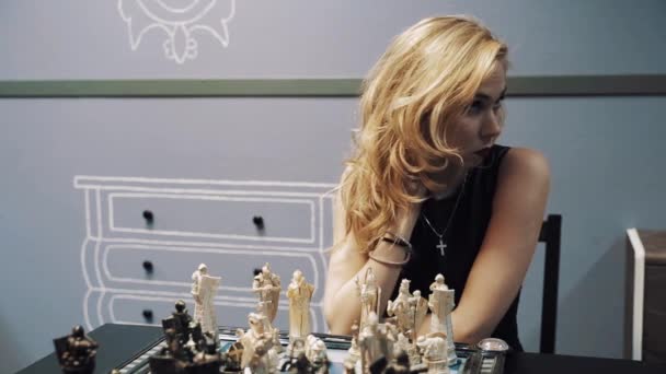 Gelangweilte junge blonde attraktive Frau streichelt Hals über Schachbrett — Stockvideo