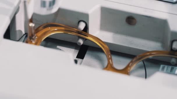 Καφέ πλαστικά γυαλιά πλαισίων σε οπτικό μέτρησης μηχάνημα — Αρχείο Βίντεο