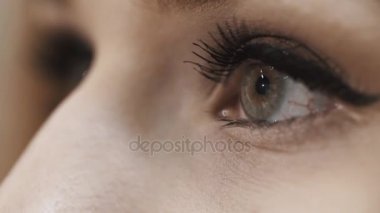 Sarışın kız gri gözleri yanıp sönüyor. Siyah rimel ve göz kalemi