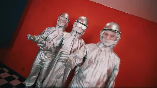Drei Männer in silbernen Overalls, harten Hüten und Brillen schnappen im Rhythmus mit den Fingern — Stockvideo