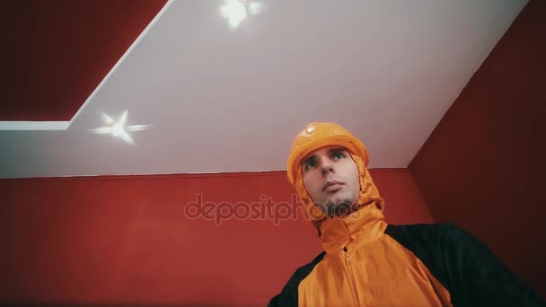 Guy in hazard jacket and orange hard hat cross armed in red room, rapping — Stock Video