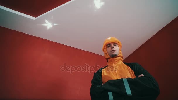 Un type vêtu d'une veste de travailleur et d'un casque orange armé en chambre rouge, frappant — Video