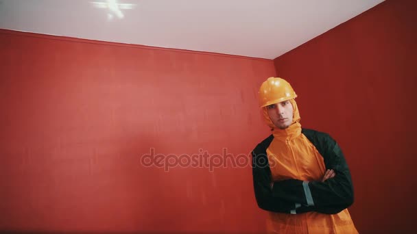 Guy in giacca costruttore e arancione hard hat croce armati in camera rossa, rap — Video Stock