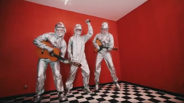 Drei Männer in silbernen Warnanzügen spielen Musikinstrumente und tanzen — Stockvideo