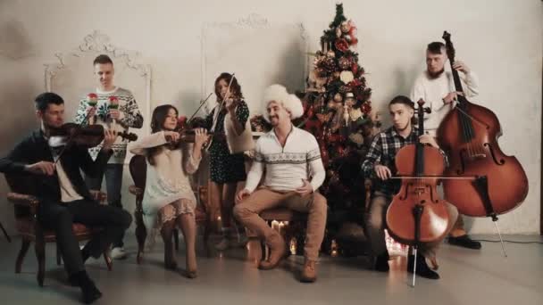 Струнный квинтет с певцом исполняет музыку в помещении с рождественскими украшениями — стоковое видео