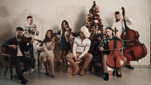 Струнный квинтет с вокалистом, играющим музыку в комнате с рождественскими украшениями — стоковое видео