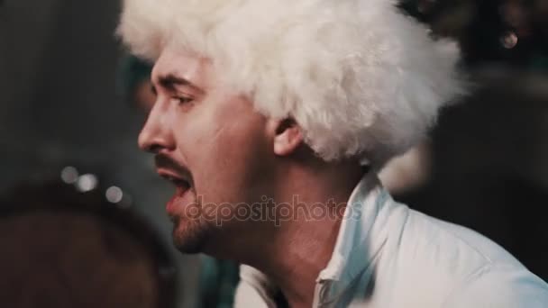 Unshaved Man In White Fur Hat Singing With String Quartet Sitting In Room