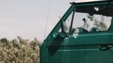 Rüzgarda sallayarak çalılar önünde park etmiş minibüs kapı