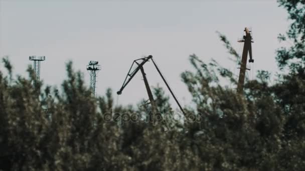 Large metal cargo cranes over behind shaking bushes — Stock Video