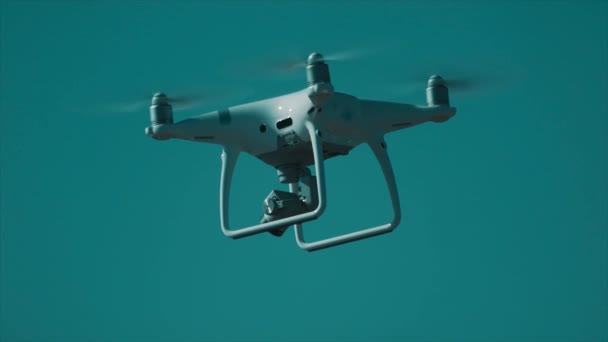 Cámara blanca quadcopter volando delante del cielo azul claro — Vídeos de Stock