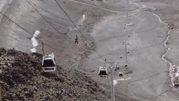Aerial lift cabins rides on cables in stony mountains — Stock Video