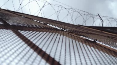 Metal tel örgü ile gri gökyüzü önünde üstte dikenli tel çit