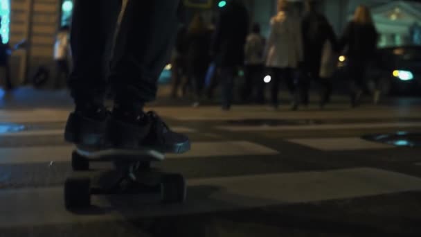 スケートボーダー人足のライド夜市道路横断歩道を渡る — ストック動画
