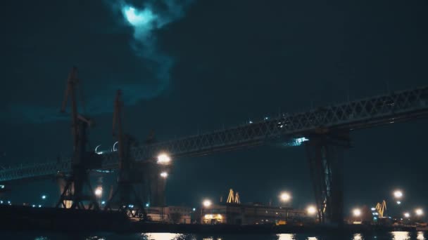 Construcción de puentes metálicos sobre el puerto de la ciudad en la noche oscura — Vídeo de stock