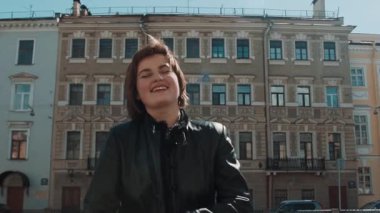 Siyah deri ceketli eski şehirde neşeli şarkıcı kız gerçekleştirir