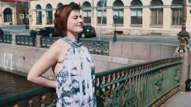 Młoda kobieta zezuje na miasto most nad rzeką — Wideo stockowe