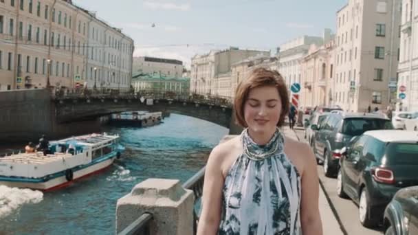 Chica bonita en vestido manchado canta a lo largo del río en el centro de la ciudad vieja — Vídeo de stock