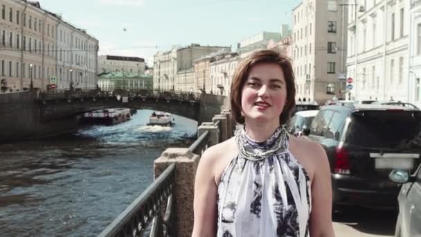 Cheerful girl in spotted dress sings along river in old city centre — Stock Video