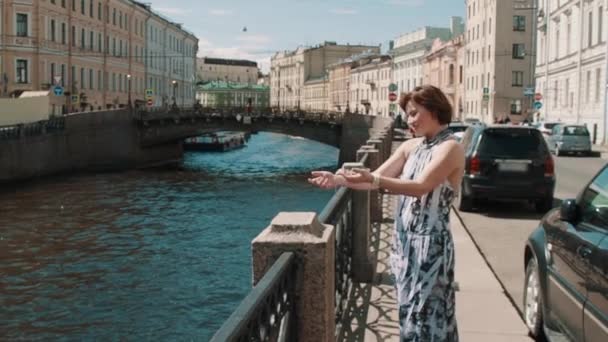 Glückliches Mädchen im fleckigen Kleid schwingt die Arme in der Nähe des Flusses in der Altstadt — Stockvideo