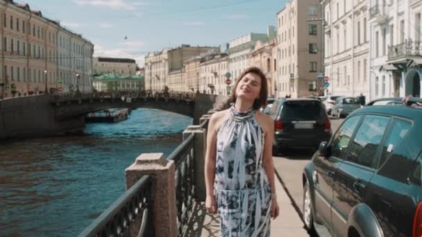 Menina sorridente em vestido manchado olha para o céu perto do rio no centro da cidade velha — Vídeo de Stock