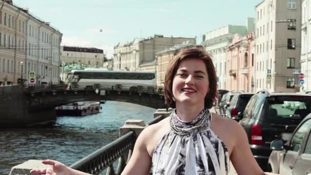 Joyful girl in spotted dress sings at embankment in old city centre — Stock Video