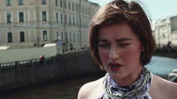Troubled giovane donna in abito macchiato canta a riva del fiume nel centro storico della città — Video Stock