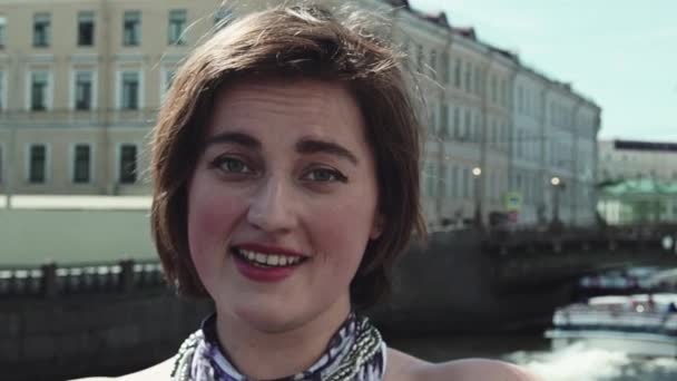 Portrait of young woman in spotted dress sings along river in old city centre — Stock Video