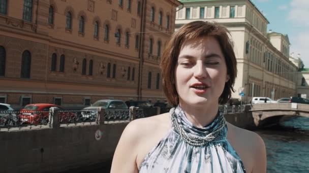 Красива дівчина в легкій сукні співає вздовж річки в старому центрі міста — стокове відео