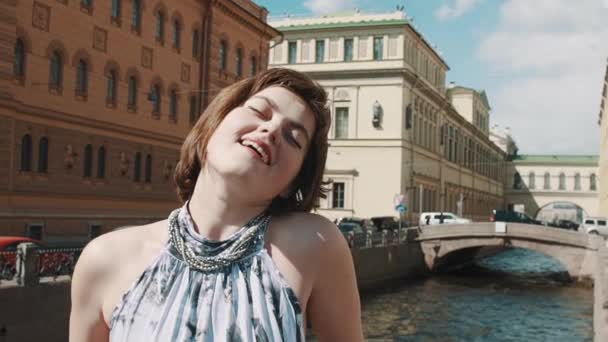 Wanita ceria dengan gaun terang bernyanyi di sepanjang sungai di pusat kota tua — Stok Video
