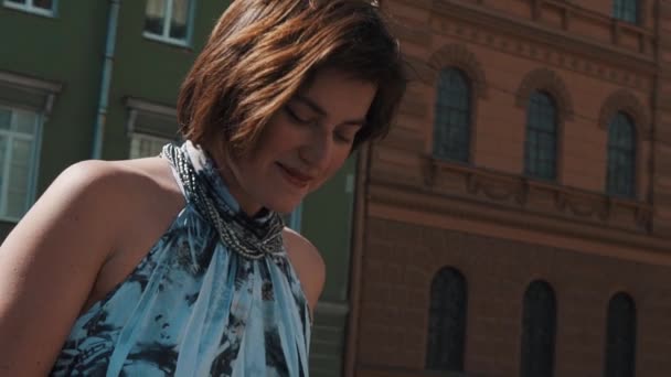 Chica vocalista alegre realiza en el casco antiguo en vestido de verano — Vídeo de stock