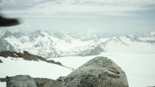 Πεζοπόρος πόδια σε δερμάτινα παπούτσι σφυροκοπήματα πάνω σε βράχο στο χιονισμένο βουνό, γραφική θέα — Αρχείο Βίντεο
