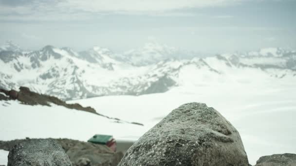 Τυχοδιώκτης πόδια σε Δερμάτινη μπότα σφυροκοπήματα πάνω σε βράχο στο χιονισμένο βουνό, γραφική θέα — Αρχείο Βίντεο