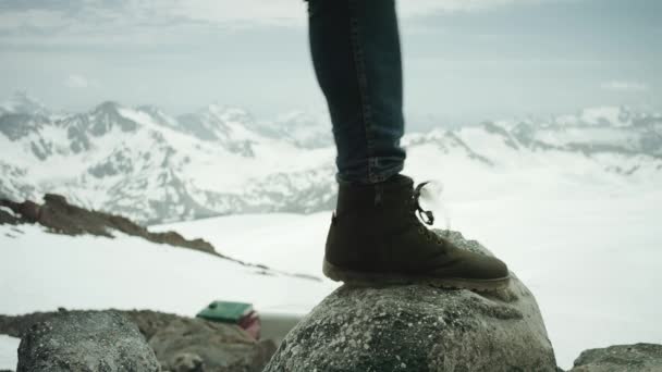 Ταξιδιώτης πόδια σε δερμάτινα παπούτσι σφυροκοπήματα πάνω σε βράχο στο χιονισμένο βουνό, γραφική θέα — Αρχείο Βίντεο