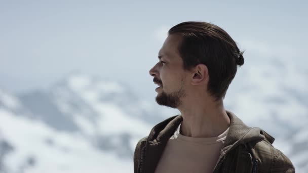 Viajero barbudo joven en la cima de la montaña con vista panorámica mirando hacia otro lado — Vídeos de Stock
