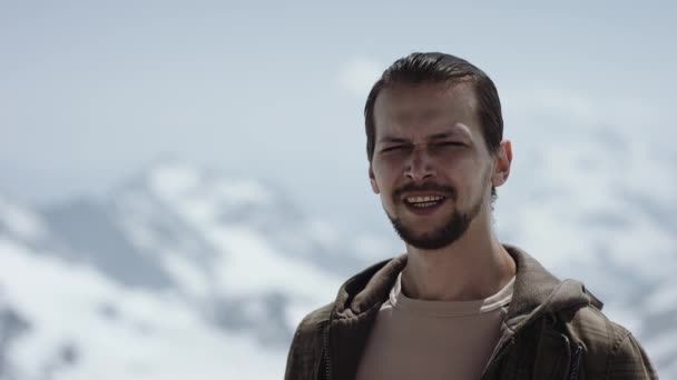 Jovem viajante barbudo no ápice da montanha com vista panorâmica olhos de squint e falando — Vídeo de Stock