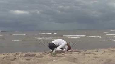 Kumlu deniz sahilinde beyaz boya kaplı sanatsal dişi çömelmiş